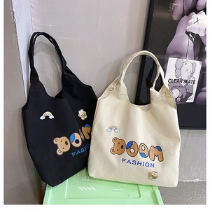 Detail der Canvas-Tragetaschen mit BOOM FASHION-Buchstaben und süßen Bären-Patches