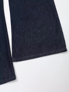 Gros plan détaillé sur la texture du denim bleu foncé et les coutures de l'ourlet