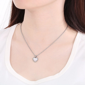 Detail of silver twisted chain necklace with heart shell pendant on model neck