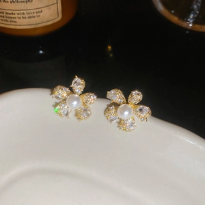 Nahaufnahme eleganter Blumen-Ohrstecker mit Kristallen und Perlen auf Keramikteller