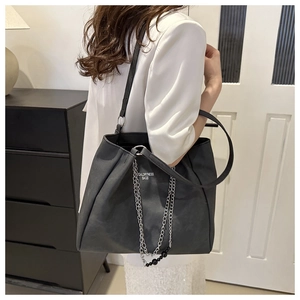 Detail of large black tote bag with silver chain strap and white brand logo lettering