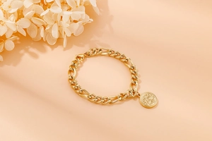 Close-up of golden stainless steel chain bracelet with a round Tree of Life coin pendant