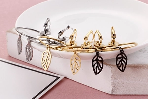 Detailed view of leaf-shaped hoop earrings in gold, silver, and black finish