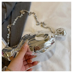 Close-up of a silver candy-shaped acrylic handbag with wrinkled texture and chain strap