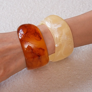 Close-up of thick amber and cream resin bangles with marble texture on wrist