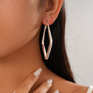 Model wearing geometric rhombus earrings in polished silver with a minimalist metal design