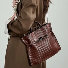 Detail of premium woven leather tote bag in dark brown with elegant metal buckle closure