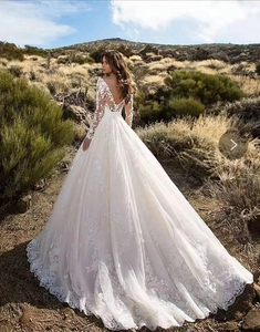 Macro detail of the elegant lace embroidery and long mesh sleeves of this bridal gown