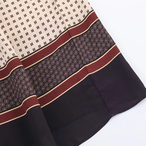 Close-up of bohemian floral print dress hem with geometric patterns and silk texture