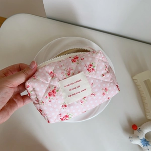 Detail of pink floral quilted cotton cosmetic bag featuring white zipper and fabric label