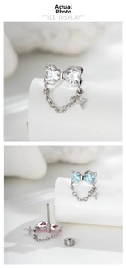 Detail view of bow earrings with crystal hearts, long chains, and tiny star charms