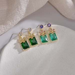 S925 silver flower stud earrings with rectangular green crystals on a white ceramic tray