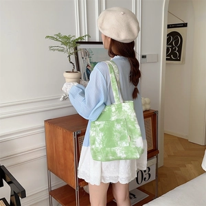 Dettaglio della borsa in tela tie-dye con motivo verde e bianco e una tasca frontale