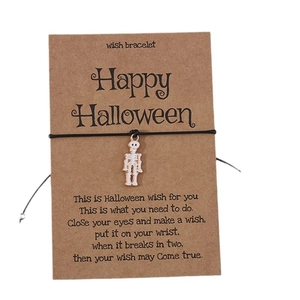 Halloween wish bracelet featuring a skull charm on cardstock with black woven cord