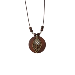 Vintage bohemian long necklace with wooden pendant and metallic leaf detail on white background