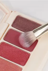 Macro shot of a professional synthetic makeup brush picking up pigmented eyeshadow powder