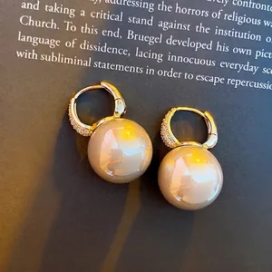 French style gold pearl hoop earrings with zircon pavé on a vintage book background