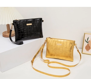 Detail view of crocodile pattern crossbody bags in glossy black and elegant gold