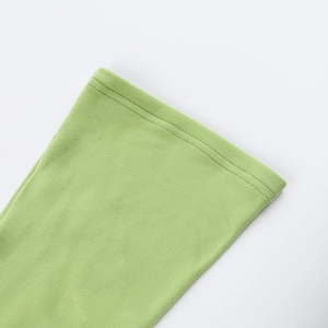 Zoom détaillé sur la texture en maille fine et l'ourlet à double couture d'une robe verte