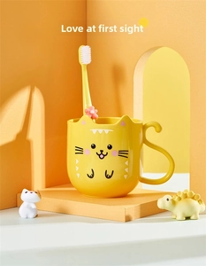 Detail of cute yellow cat themed mouthwash cup with matching toothbrush and tail handle