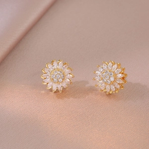Close-up of elegant gold sunflower stud earrings with shimmering crystal petals on silk