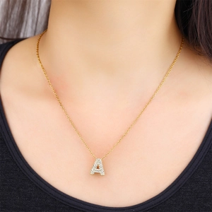 Close-up of a gold-plated letter A pendant necklace with sparkling cubic zirconia on a model