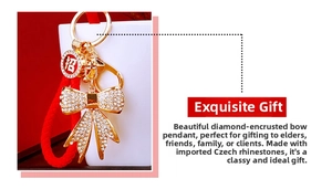 Detailed view of golden bow keychain with white crystals and a red braided strap