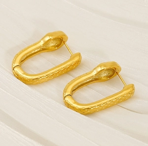 Détails de boucles d'oreilles dorées avec texture d'écailles de serpent sur tissu