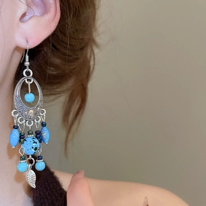 Close-up of vintage turquoise leaf tassel earrings on a model showing intricate details