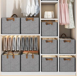 Gray fabric storage box with brown handles organized on a white shelf in a closet