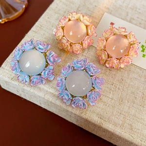 Detail of floral earrings with enamel roses and colorful resin centers on display