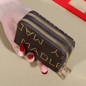 Close-up of a brown leather double zipper coin purse with embossed letters and gold hardware