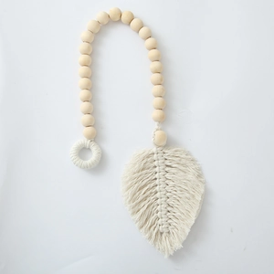 Detail of bohemian hand-woven curtain tieback with wooden beads and cotton leaf pendant