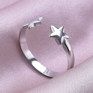 Detail view of silver stainless steel adjustable ring with a twin star design on pink satin