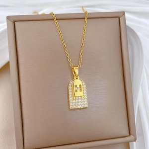 Close-up of golden necklace featuring an H-shaped pendant set with sparkling cubic zirconia