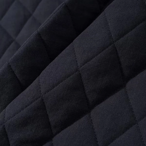 Macro shot of black diamond-quilted fabric detailing with precise stitching and soft texture