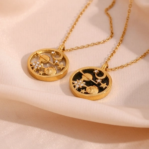 Close-up of gold star and moon coin necklaces on soft pink fabric background