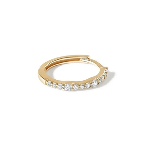 Close-up of gold huggie hoop earring with shimmering inlaid stones on white background