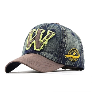 Vintage denim baseball cap with W-patch, fringe details, and brown brim on white background