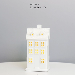 Detailed close-up of a white ceramic house night light with warm LED glowing through windows