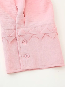 Detail of pink blouse cuff with triangular fold design and matching buttons