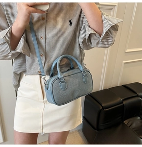Detail of light blue textured Boston bag with silver hardware and leather straps