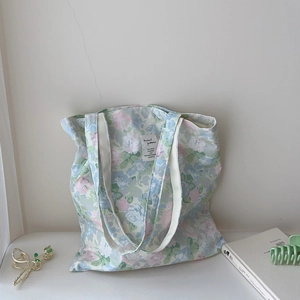 Detail of floral canvas tote bag featuring pastel prints and woven rectangular label