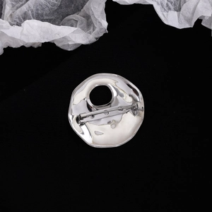 Macro shot of the pin fastener and textured back of a silver hollow round brooch
