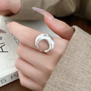 Macro shot of silver crescent wave geometric ring with hollow adjustable opening design