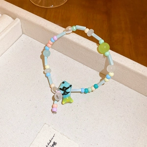 Close-up of macaron-colored ceramic beads and a turquoise fish charm on a woven bracelet