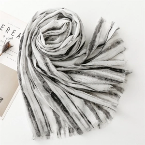 Detail of grey ink gradient scarf with gold foil accents and frayed edges on white background