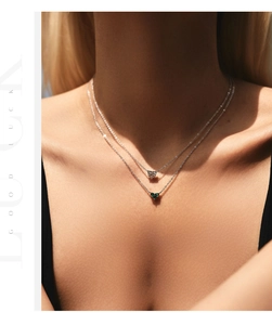 Close-up of s925 silver layered necklaces with green and white heart-shaped stone pendants