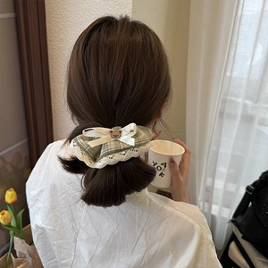 Green plaid scrunchie with beige lace and bear charm worn on a low ponytail hair