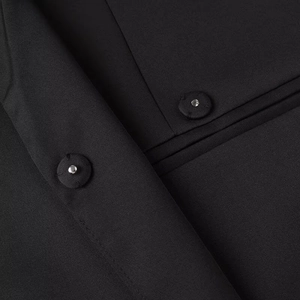 Detailed close-up of blazer collar and snap button showing the high-quality fabric texture